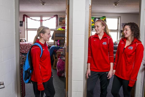 Female students smiling in front of their dorm rooms