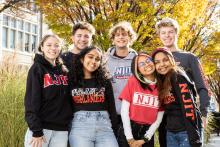 Group of diverse students smiling on campus in front of trees