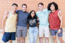 Diverse group of students standing together outside in front of a building on campus